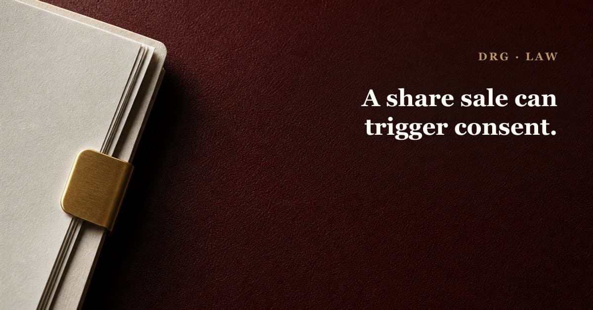 A brass key clasping legal papers on an oxblood surface